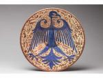 PLAT circulaire en faïence à décor lustré d'un aigle bleu...