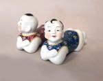 Deux sujets en porcelaine, représentant les frères Hoho allongés. 
Chine,...