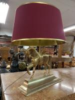 LAMPE en métal doré à décor d'un cheval, l'abat-jour rouge...