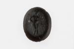 INTAILLE en pierre noire à décor d'une femme nue tenant...
