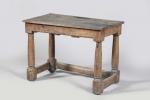 TABLE en bois naturel à ceinture surmontant quatre larges colonnes...